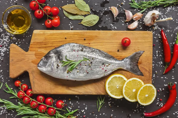 Vista desde arriba de la composición de los alimentos con pescado crudo e ingredientes en tablero de madera - foto de stock