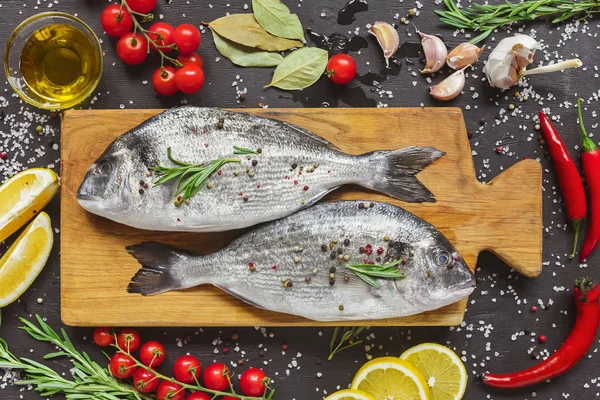 Вид сверху на пищевой состав с сырой рыбой и ингредиентами на черном столе — стоковое фото