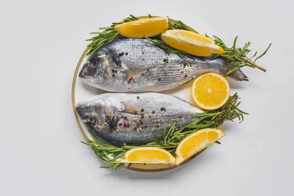 Flat lay with fish decorated by rosemary and lemon on plate — Stock Photo