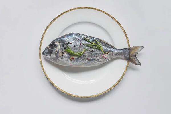 Vista superior de peixes não cozidos com alecrim e pimenta no prato — Fotografia de Stock