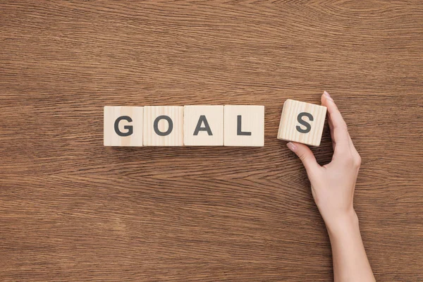 Cropped view of person adjusting 'goals' word made of wooden blocks on wooden tabletop, goal setting concept — Stock Photo