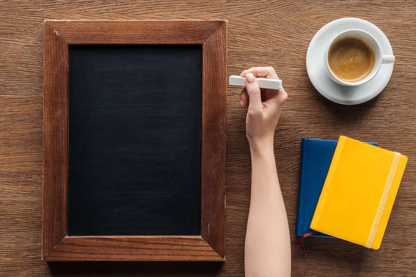 Vista recortada de la escritura de la mujer con tiza en tablero de madera en blanco - foto de stock