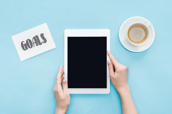 Vista recortada de la mujer celebración tableta digital con pantalla en blanco ob fondo azul - foto de stock