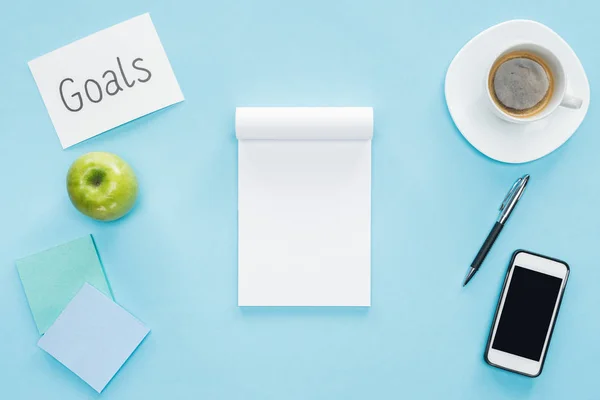 Notebook von oben auf blauem Hintergrund, Smartphone mit leerem Bildschirm, Kaffee und Notizen — Stockfoto