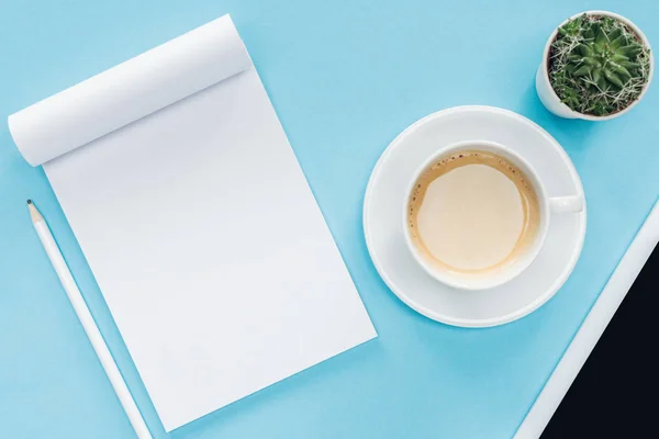 Vista superior del cuaderno en blanco con lápiz, taza de café sobre fondo azul - foto de stock