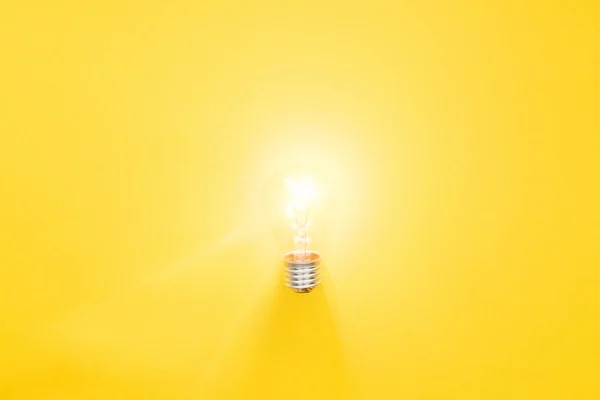 Glowing light bulb on yellow background, having new ideas concept — Stock Photo
