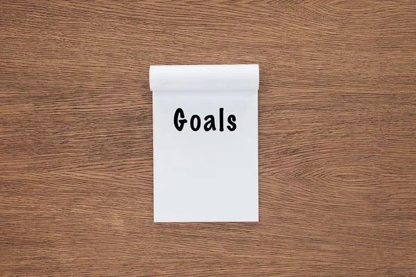 Top view of notebook with 'goals' lettering on wooden background — Stock Photo