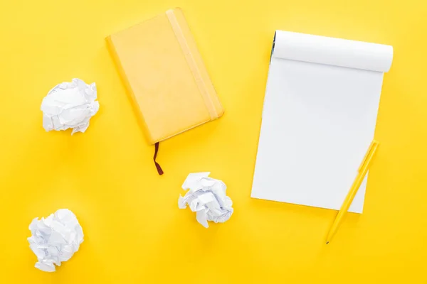 Notebook em branco e bolas de papel desmoronadas no fundo amarelo — Fotografia de Stock