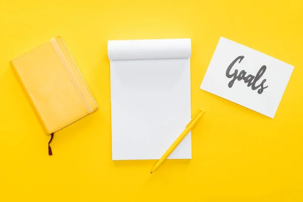 Blank notebook and card with 'goals' lettering on yellow background, goal setting concept — Stock Photo