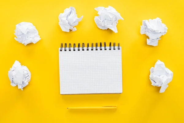 Blank spiral notebook and crumbled paper balls on yellow background — Stock Photo