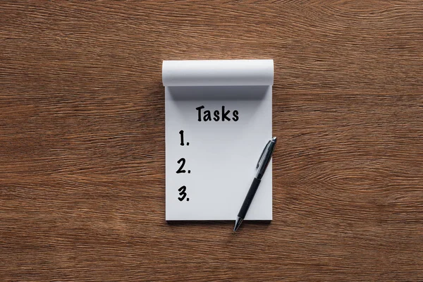 Word 'tasks' in notebook on wooden background — Stock Photo