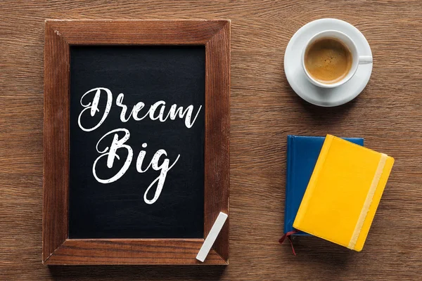Top view of chalk board with 'dream big' lettering on wooden background — Stock Photo