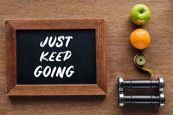 Fruits, dumbbells, measuring tape and wooden chalk board with 'just keep going' quote, dieting and healthy lifesyle concept — Stock Photo