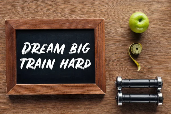 Apple, dumbbells, measuring tape and wooden chalk board with 'dream big train hard' quote, dieting and healthy lifesyle concept — Stock Photo