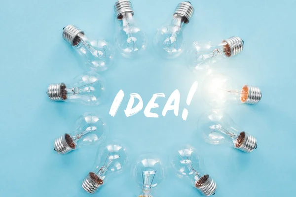 Circle of light bulbs with glowing one surronding 'idea' word, having new ideas concept — Stock Photo