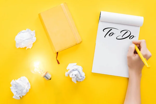 Cropped view of notebook with 'to do' list, crumbled paper balls and glowing light bulb, goal setting concept — Stock Photo