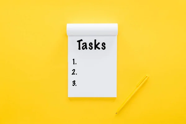 Top view of notebook with tasks list on yellow — Stock Photo