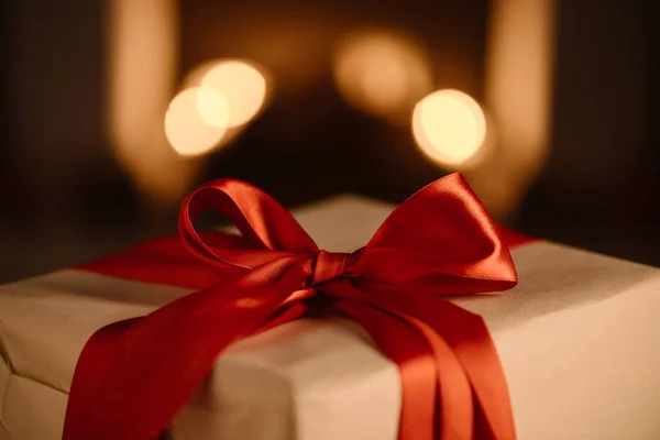 Present with red bow on blurred background — Stock Photo