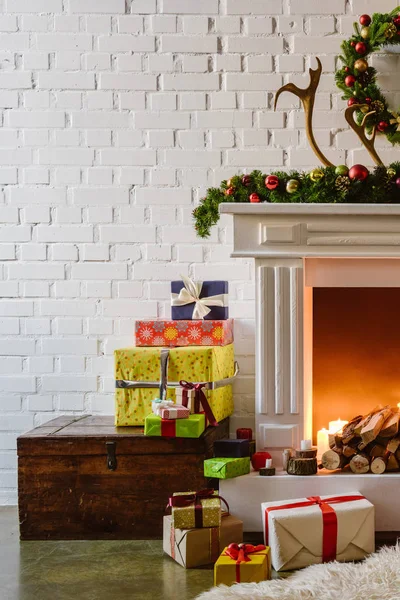 Christmas decorations with gift boxes near warm fireplace in living room — Stock Photo