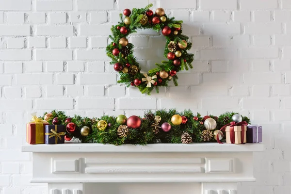 Corona de Navidad y decoraciones sobre chimenea mantel con pared de ladrillo blanco - foto de stock