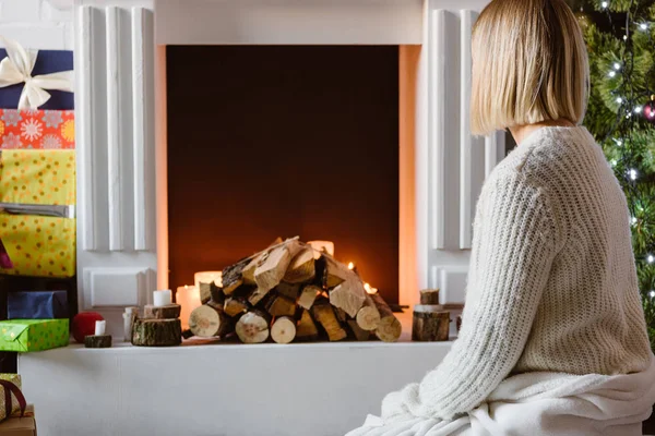 Young woman sitting and looking at fireplace — Stock Photo