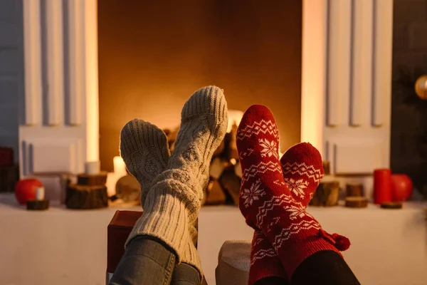 Cropped view of women wearing winter socks with fireplace on background — Stock Photo