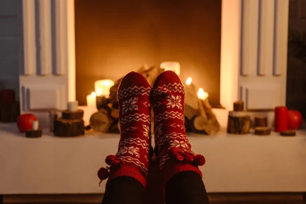 Cropped view of woman in festive winter socks with fireplace on background — Stock Photo