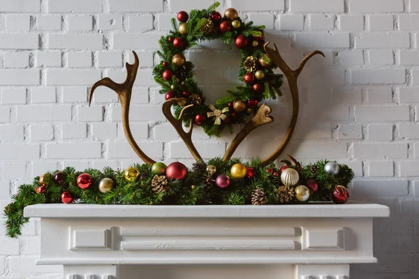 Christmas wreath with decorations and deer horns over fireplace mantel — Stock Photo