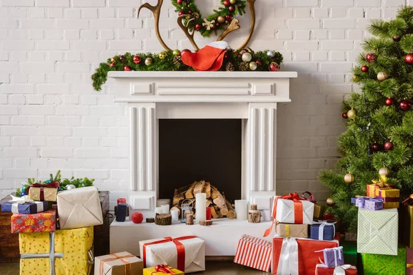Décorations festives sur cheminée avec boîtes cadeaux et arbre de Noël — Photo de stock