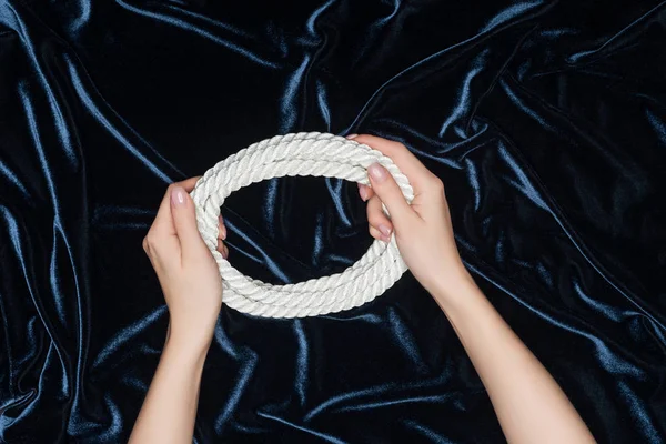 Vista cortada de mãos femininas segurando corda no fundo de veludo — Fotografia de Stock