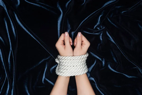 Cropped view of female hands tightly bounded with rope on velvet background — Stock Photo