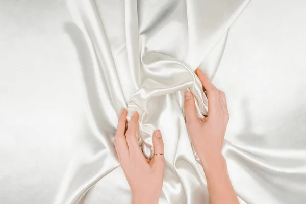 Cropped view of female hands gently holding white satin cloth — Stock Photo