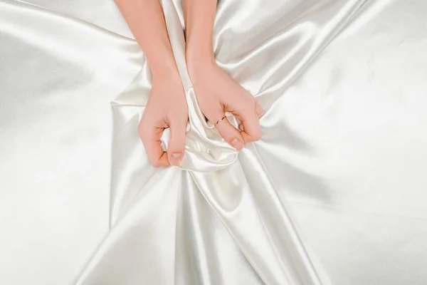Cropped view of female hands tightly holding shiny satin cloth — Stock Photo