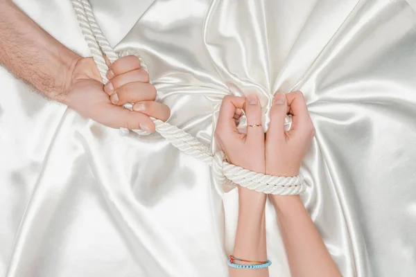 Cropped view of male hand bounding female hands with rope — Stock Photo