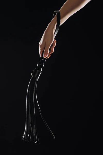 Cropped view of female hand holding leather flogging whip isolated on black — Stock Photo