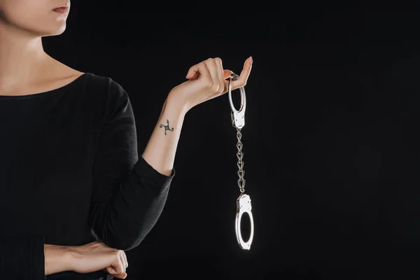 Partial view of woman holding metal handcuffs isolated on black — Stock Photo