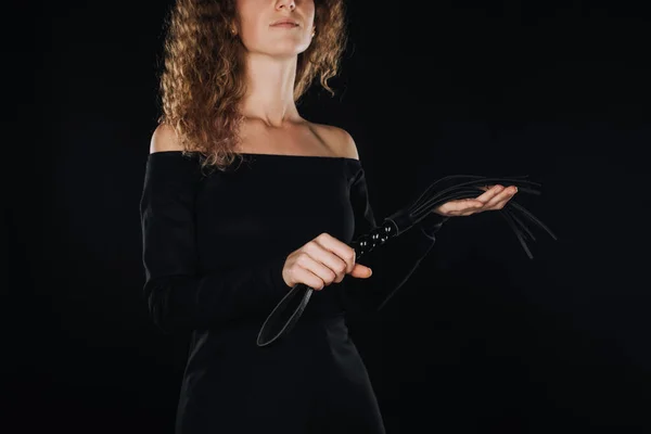 Curly adult woman holding flogging whip isolated on black — Stock Photo