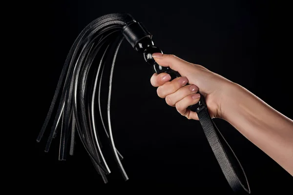 Partial view of female hand holding leather flogging whip isolated on black — Stock Photo