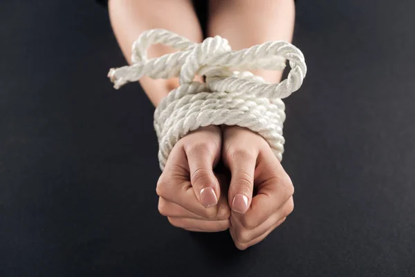 Vista ritagliata di mani legate femminili con corda isolata su nero — Foto stock