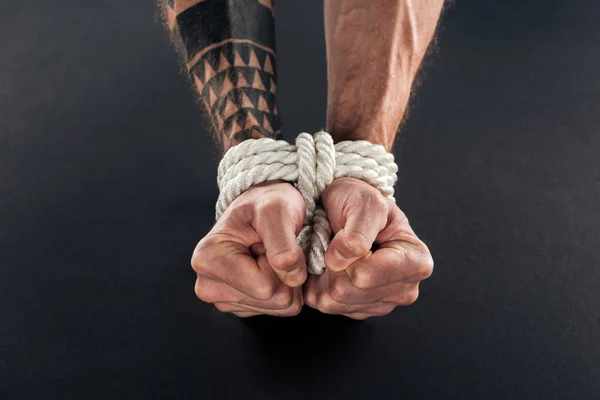 Cropped view of bound male hands with tattoo isolated on black — Stock Photo