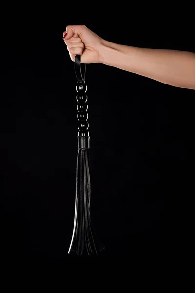 Partial view of woman holding leather flogging whip in fist isolated on black — Stock Photo