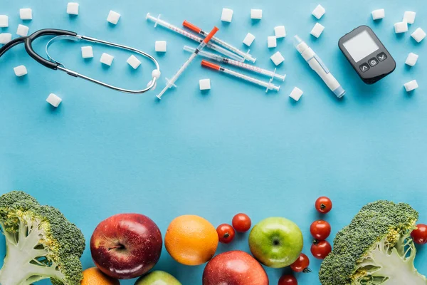 Equipo médico, terrones de azúcar y frutas con espacio para copiar sobre fondo azul - foto de stock