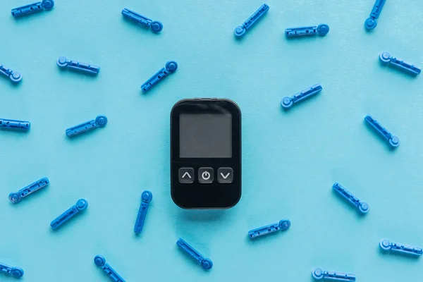 Équipement médical pour le contrôle du diabète avec aiguilles jetables sur fond bleu — Photo de stock