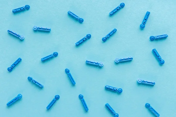 Верхний вид одноразовых игл в рассеянном виде на голубом фоне — стоковое фото