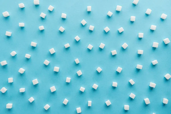 Top view pattern made of sugar cubes on blue background — Stock Photo