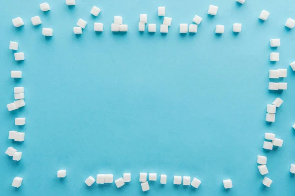 Vue du dessus du cadre en cubes de sucre avec espace de copie sur fond bleu — Photo de stock