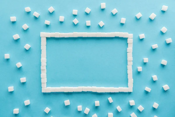 Flat lay of frame made of sugar cubes with copy space on blue background — Stock Photo