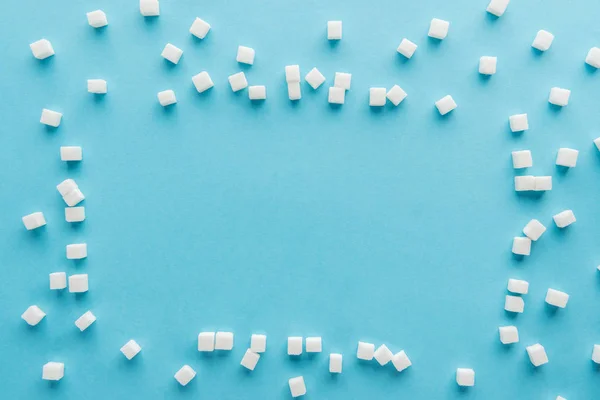 Верхний вид рамки с кубиками сахара и копировальное пространство на синем фоне — стоковое фото