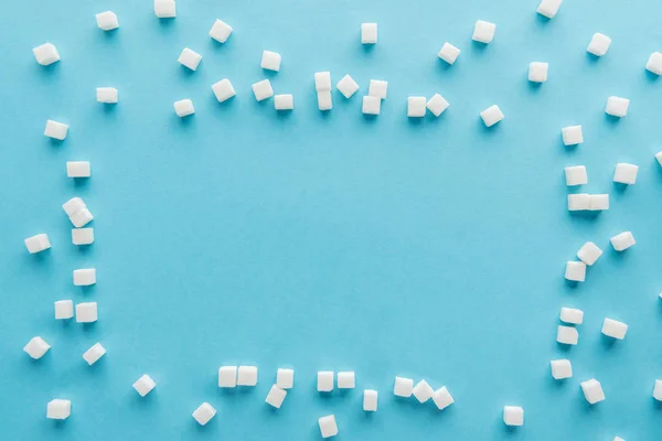 Vue de dessus du cadre faite avec des cubes de sucre et l'espace de copie sur fond bleu — Photo de stock