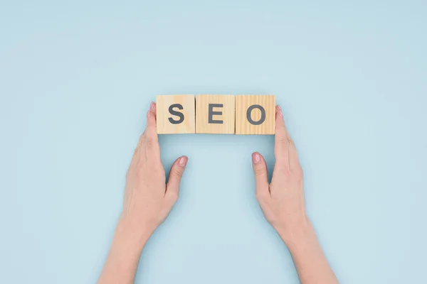 Top view of female seo manager holding wooden blocks on light blue background — Stock Photo